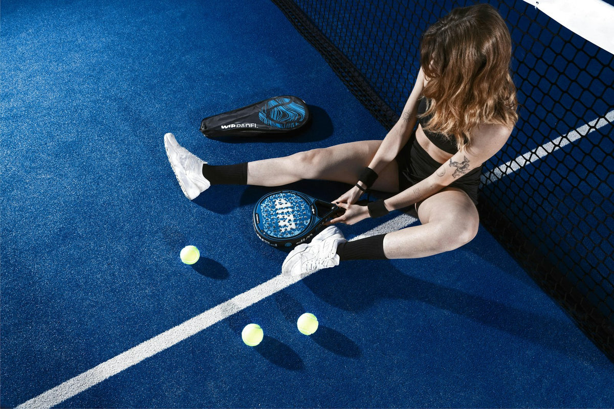 Jugadora de pádel sentada en la pista descansando entre puntos